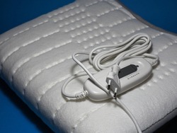 Electric heating pad on a blue background. Comfort and health. Heating pad with temperature and time control options
