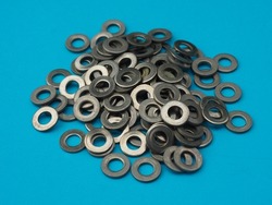 Flat metal washer. A pile of metal washer on a blue background. A scattering of metal washers for bolts and screws
