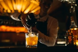 The bartender squeezes citrus juice into a cocktail