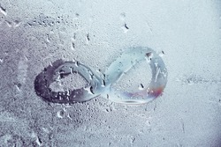 Concept with an infinity sign on a wet window.