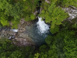 Blue Eye Theth Lake Waterfall in Theth (Thethi) National Park in north of Albania, beautiful place with cold blue water and green forest around, aerial footage on the drone from above
