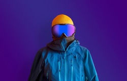 Snowboarder in full outerwear isolated over a dark purple background. Winter sports fashion. 