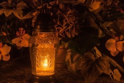 Orange grave lantern shining with light. Cemetery at night. Catholic Halloween tradition. All souls' day in Poland, Eastern Europe. Zaduszki.
