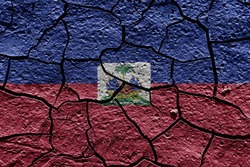 Haiti flag on a mud texture of dry crack on the ground
