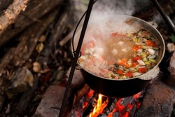 A pot of hot food in the forest, outdoor recreation at night. Hiking, travel and wilderness recreation, cooking soup over the fire.