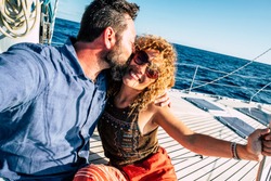 Happy tourist couple of traveler people in love enjoying the sail boat trip together having fun and smiling - cheerful adult man and woman under the summer sun in holiday vacation at the sea