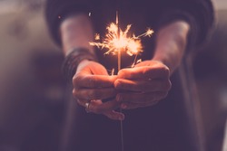 Concept of party nightlife and new year eve 2020 - close up of people hands with red fire sparklers to celebrate the night and the new start - warm colors filter - joy and hope concept life