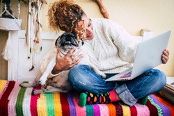 Cheerful adult caucasian. woman work happy with tablet computer hugging her best friend old funny dog pug - coloured image for happiness concept and animals love therapy