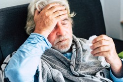 New coronavirus CoVid-19 outbreak situation with pandemic epidemic warning - adult caucasian senior old man with fever symptoms like illness cold seasonal influenza - people and virus concept