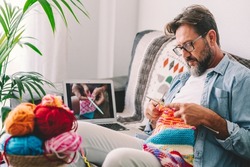 One adult man at home follow online knit tutorial to relax and enjoy resting home leisure activity sitting on the sofa - male people knitting with computer class help - people inner lifestyle hobby