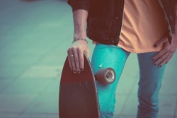 Close up of boy hand with black nails holding skate board with city asphalt street in background - concept of youthful people lifestyle and stylish alternative style - modern male teenager transport
