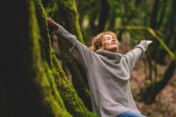 Overjoyed happy woman enjoying the green beautiful nature woods forest around her - concept of female people and healthy natural lifestyle - happiness emotion and adult lady opening arms 