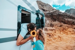 Couple of traveler kiss and love at destination. Man inside camper van and woman outside in relationship. Happiness and traveler lifestyle. Modern rv vehicle for road trip holiday vacation. Off grid