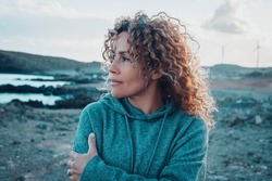 Concept of young woman and emotions. Inner balanced portrait of female enjoying freedom and sensations outdoor. Travel and wanderlust lifestyle people. Beautiul lady with curly long hair smiling