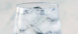 banner with close up glass with ice water and ice cubes on white textured background. A refreshing and chilling drink in hot weather. soft focus