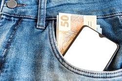Money and Cell Phone with blank screen in jeans pocket.