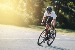 Cyclist pedaling on a racing bike outdoors in sun set .The image of cyclist in motion on the background in the evening.