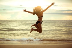 Happy Asian woman jumping on the beach. Summer vacation concept,Sunset ,hight key.