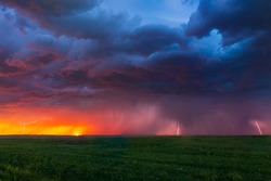 Lightning bolts strike at sunset along the Wyoming and Colorado border. The last remnants of the sun can be seen setting along the horizon with color hues of pinks, purples, reds, and oranges.