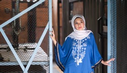 Beautiful young arabic girl in hijab posing for a camera on rustic background. Hijab fashion portraiture.