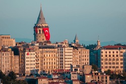 Galata Tower is located in the Beyoğlu district of Istanbul. As the sun sets, its lights reflect on the Galata tower and buildings. The Turkish flag hanging on the Galata Tower. Istanbul, Turkey.