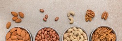 Nut background. Banner for large format printing, advertising and website design. Nuts of different varieties lie in bowls on a stone countertop, top view. Peanuts, cashews, almonds, walnuts.