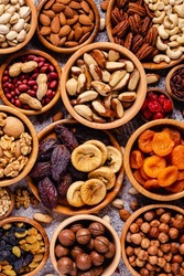 Various Nuts and dried fruits in wooden bowls, top view.