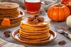 Stack of homemade pumpkin pancakes with pecans and maple syrup, selective focus.