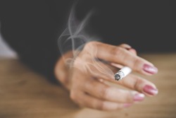 closeup woman hand smoking cigarette ,unhealthy lifestyle concept 