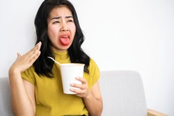 Asian woman eating very hot and spicy noodle from a cup her mouth and tongue burning and red 