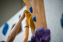 Arms reaching a climbing holder on a climbing wall