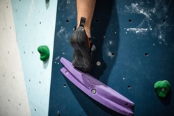 Close-up of a climbing shoe standing up to reach a new hold on the climbing wall.