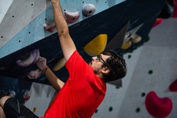 Man holding a climbing hold on a climbing wall