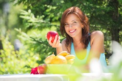 Happy Smiling Young Woman Eating Organic Apple at her Garden