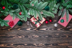 Christmas background with fir branches, cones and gift boxes on dark wooden background. Flat lay with Christmas ornaments