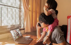 Virtual Conference scene between Asian man with daughter over shoulders doing virtual meeting with his boss, concept work from home while covid-19 crisis, online training class room, Social distancing