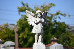 A sculpture of a praying cherub in a cemetery