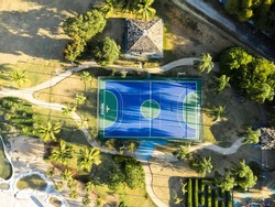 Aerial view of blue multi-sport court in the park. Used to practice football, basketball or volleyball. Top view. Sunny day. Sunset. Drone photo.