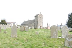 A scenic church countryside setting with grave headstones containing carved inscriptions. Monumental masonry and beautiful architecture with old buildings and monuments in a peaceful tranquil location