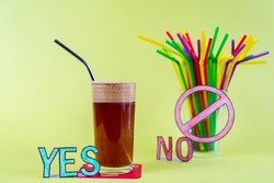 Yes to the metal straw, no to the plastic straws. A glass of cold frappe coffee with metal straw and a glass full of plastic colorful straws with a red prohibition sign