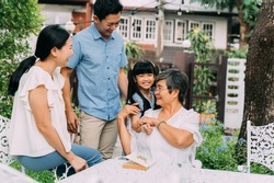 Group of multi-generational Asian family enjoying a good time together in backyard garden and smiling with happiness