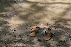 Flip flop taken off by the water under the shadow of a tree
