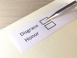 One person is answering question on a piece of paper. The person is thinking to be disgrace or honor.