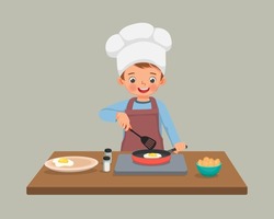 cute little boy chef cooking delicious fried egg with frying pan in the kitchen