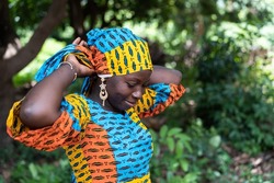 Beautiful black African woman fixing her colored scarf on her head