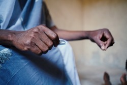 Close up hand holding silver razor blade to symbolize FGM in African poor communities household