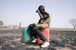 African teenager strained for walking long distance to collect clean water. Water scarcity and drought symbol.