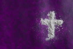 Cross of ashes on a dark purple background with copy space