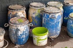 Industrial Waste, Plastic barrels of paint. High Angle View Of Liquids In Containers Against Wall. Dirty containers with stains of dye. Barrel covered with multicolored spots.