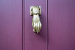 Beautiful hand sculpture as a door knocker on a purple door